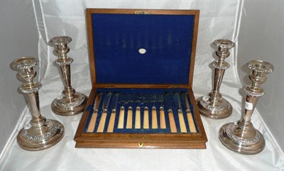 Lot 202 - Set of four silver plated candlesticks and a walnut canteen of plated fish eaters (5)