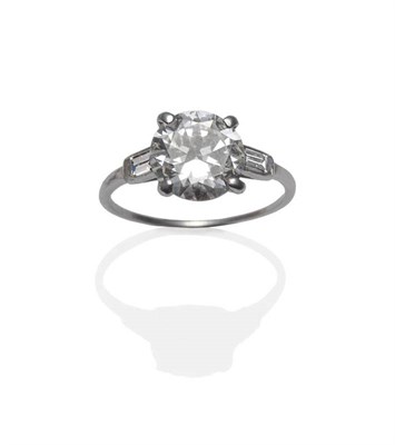 Lot 448 - A Diamond Ring, by Cartier, the old brilliant cut diamond in a white four claw setting, flanked...