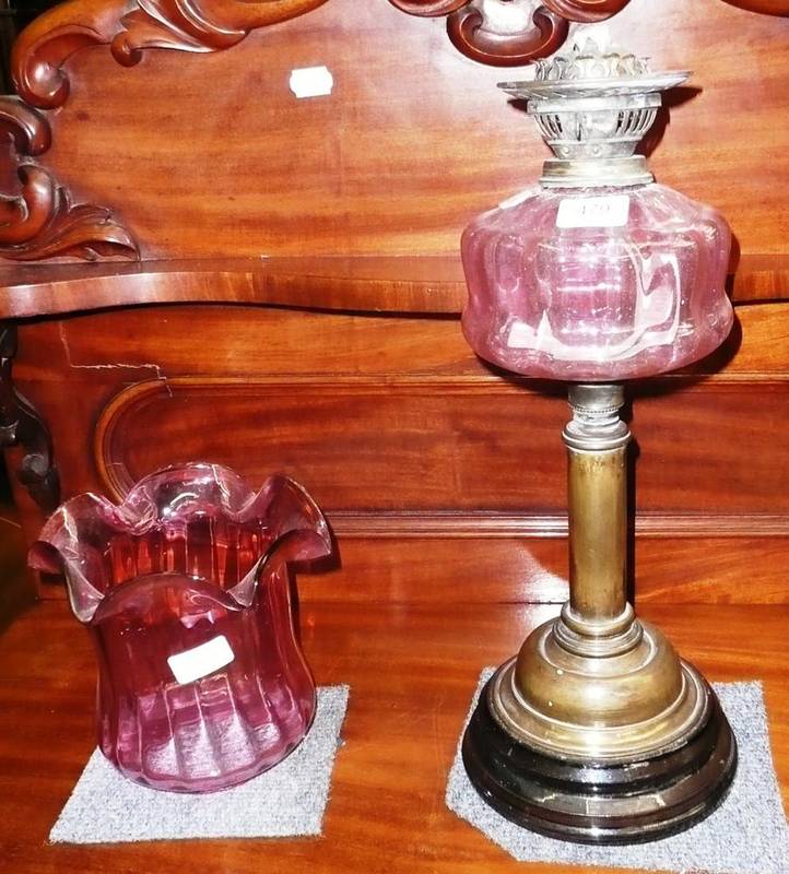 Lot 479 - Cranberry glass and brass table oil lamp and shade