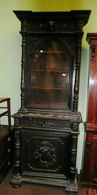 Lot 722 - A heavily carved and ebonised oak cabinet with glazed top