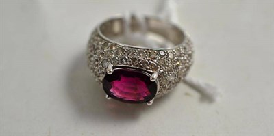 Lot 261 - A pink/purple tourmaline and diamond ring, the oval mixed cut tourmaline within a chunky...