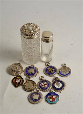 Lot 381 - Two silver topped glass bottles and ten silver enamel medals