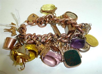 Lot 335 - A charm bracelet hung with twenty two charms, including a spade guinea, fobs, and a compass