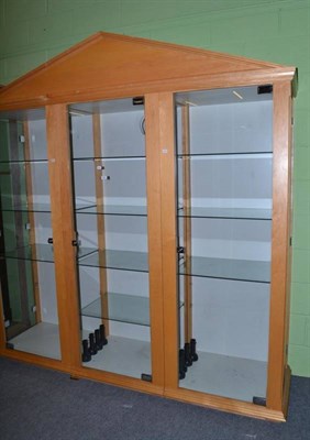 Lot 424 - A modern three door glazed display cabinet with pediment and glass shelves