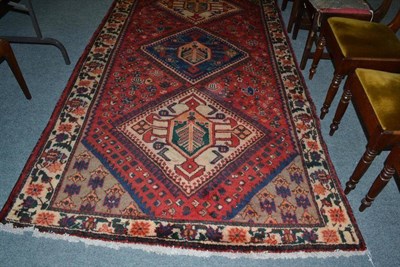 Lot 572 - Luri carpet West Persia, the tomato red field with three hooked medallions enclosed by ivory...