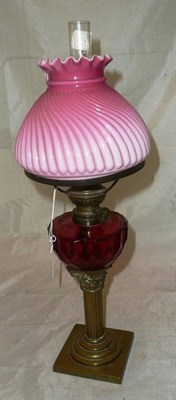 Lot 55 - A brass and cranberry glass oil lamp and shade
