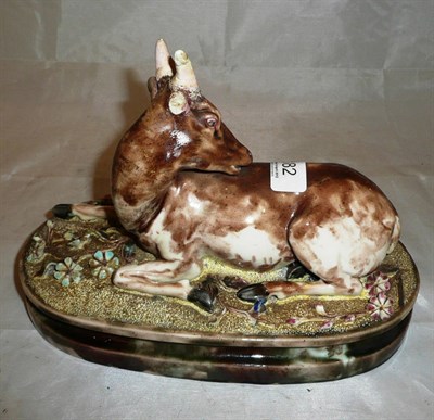 Lot 182 - A Continental porcelain model of a recumbent goat with majolica type glaze