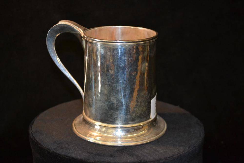 Lot 804 - An Arts and Crafts Silver Mug, by Omar Ramsden, hammered effect, with tapering scroll handle...