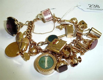 Lot 238 - A curb bracelet hung with twenty three charms including seal fobs and a shield back half sovereign