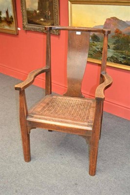 Lot 896 - An Arts and Crafts Oak Arm Chair, with curved top rail over a shaped solid splat, drop-in cane...