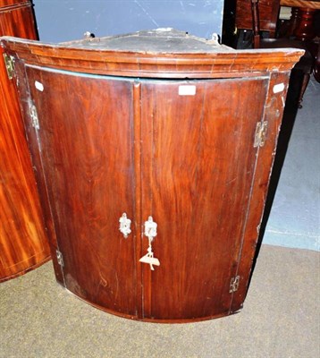 Lot 614 - A Georgian mahogany bow front corner cabinet