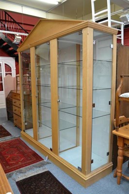 Lot 664 - A modern three door glazed display cabinet with pediment and glass shelves