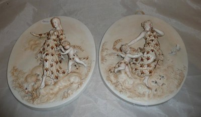 Lot 105 - A pair of Continental bisque wall plaques depicting maidens with cherubs