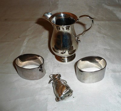 Lot 161 - Two silver napkin rings, small silver cream jug and rabbit rattle (4)