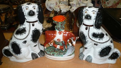 Lot 414 - A Staffordshire spill vase modelled as a cow and calf and a pair of large Staffordshire dogs