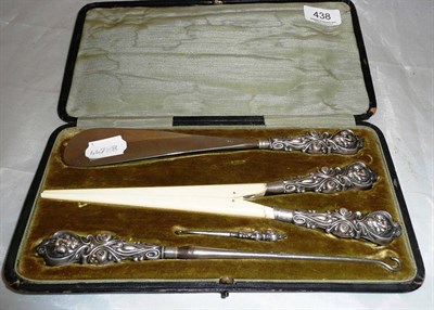 Lot 438 - Cased button hooks, tongs and a shoe horn, silver mounted, Birmingham 1902