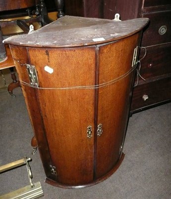 Lot 665 - An oak bow-front corner cupboard