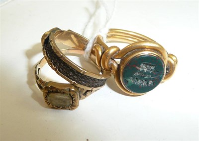Lot 64 - A bloodstone intaglio signet ring, a mourning ring and a claddagh ring with entwined hair to...