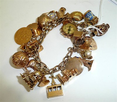 Lot 74 - A charm bracelet with engraved padlock hung with twenty three charms and soldered 1907 sovereign
