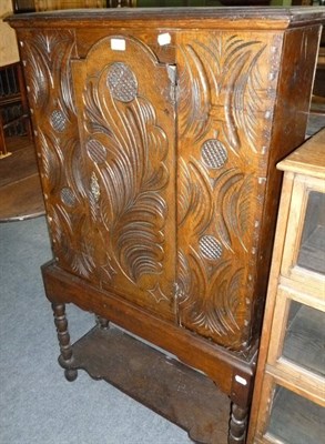 Lot 438 - A carved oak small cupboard on stand