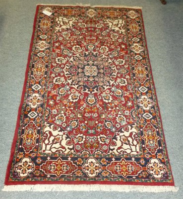 Lot 475 - An Indian rug, the ox blood field with central medallion enclosed by cartouche borders