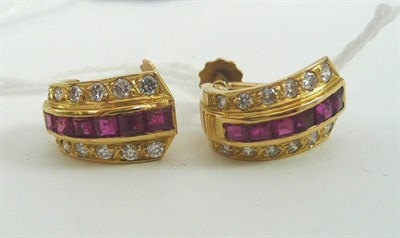 Lot 18 - A pair of ruby and diamond cuff earrings, a line of square cut rubies in a yellow rubbed over...