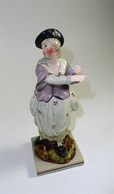 Lot 247 - # A Pearlware figure of a girl, early 19th century, standing in a pink jacket on a rocky base...