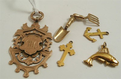 Lot 325 - # A 9ct gold cutaway shield and four charms - a fork and trowel, an anchor, a cross and a fish