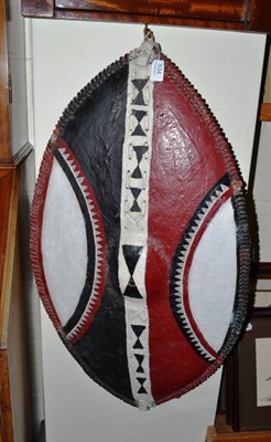 Lot 534 - A Kikuyu hide dance shield, of elliptical form, painted with curved panels and chevron bands in...