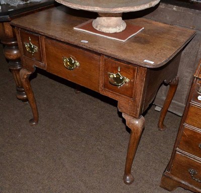 Lot 617 - A George III oak lowboy or dressing table with three frieze drawers raised on cabriole legs...