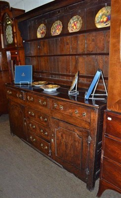 Lot 666 - An 18th century oak enclosed dresser and rack, the bold cornice above three fixed shelves, the base