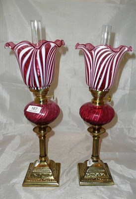 Lot 167 - Matching pair of bronze and cranberry glass small oil lamps