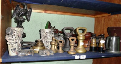 Lot 315 - * Shelf of ornamental items including a door stop, six brass bell weights, flat weights,...