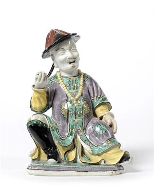 Lot 60 - A Chinese Porcelain Figure of a Gentleman, Kangxi, seated wearing a conical hat, flowing robes...