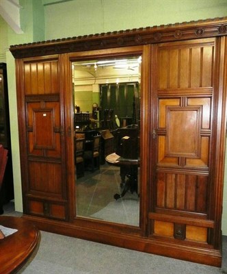 Lot 598 - * A large Arts & Crafts walnut triple door wardrobe