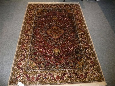 Lot 615 - Kashmir silk rug North west India, the deep claret field of scrolling vines around an indigo...