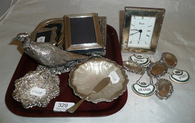 Lot 329 - A filled silver figure of a pheasant, a silver butter dish, four silver decanter labels, four...