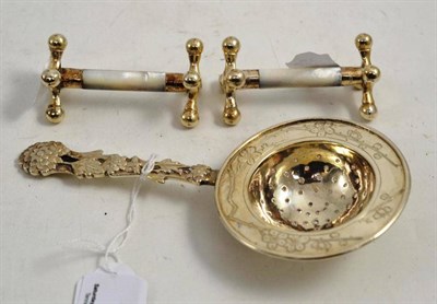 Lot 79 - A white metal strainer and a pair of knife rests