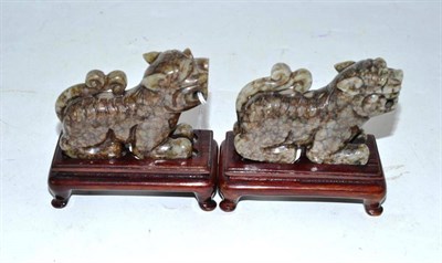 Lot 184 - A pair of Chinese hardstone Buddhist lions with wood stands