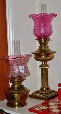 Lot 295 - A Maple London brass table oil lamp and cranberry glass shade and a Harrods brass oil lamp with...