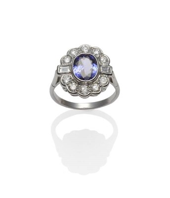 Lot 235 - A Tanzanite and Diamond Cluster Ring, an oval cut tanzanite within a border of round brilliant...