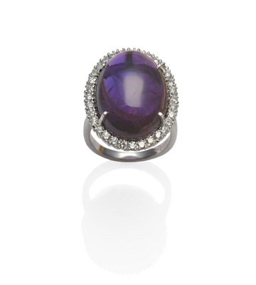 Lot 259 - An 18 Carat White Gold Cabochon Amethyst and Diamond Cluster Ring, the amethyst within a border...