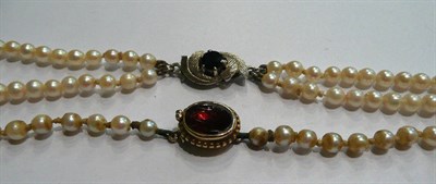 Lot 88 - Two strand pearl necklace with white gold snap in case, and a pearl necklace with garnet snap