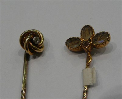 Lot 210 - A diamond set knot stick pin and a trefoil stick pin enclosing hair (2)