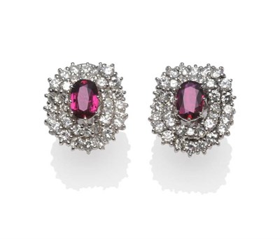 Lot 285 - A Pair of Ruby and Diamond Cluster Earrings, an oval cut ruby centres two undulating borders...