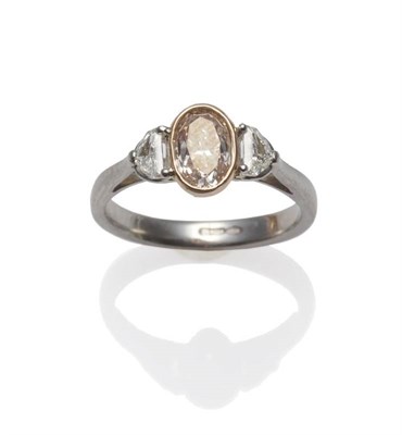 Lot 295 - A Platinum Pink Diamond Ring, the oval cut diamond in a rose gold collet setting between two...