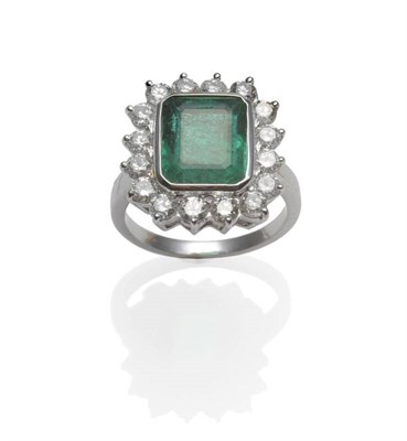 Lot 303 - An Emerald and Diamond Cluster Ring, the emerald-cut emerald within a white rubbed over...