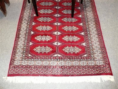 Lot 491 - Bokhara rug Probably Lahore, the blood red field with two columns of medallions enclosed by...