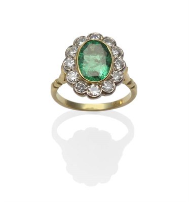 Lot 307 - An Emerald and Diamond Cluster Ring, the oval mixed cut emerald in a yellow collet setting,...