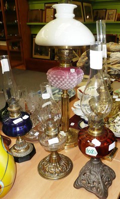 Lot 380 - Five assorted brass and other column oil lamps with coloured glass wells, chimneys and one shade